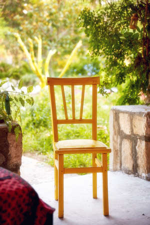 Empty yellow wooden chair at the entrance of the garden of a country home