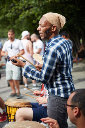 Montreal, Canada - June, 2018. African American male percussionist plays rhythm with a cow bell at Tam Tams festival in Mount Royal Park, Montreal, Quebec, Canada. Editorial use.のeditorial素材