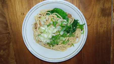 Noodles with meat and vegetables in white bowl on wooden tableの写真素材