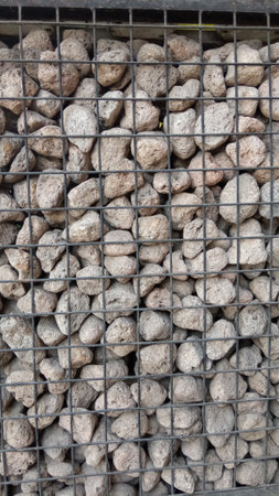 Pile of stone pebbles in a metal grid for backgroundの写真素材