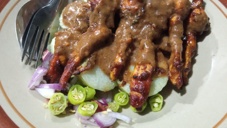 Madurese style chicken skewers served with peanut sauce, chili, and red onion on the plateの写真素材
