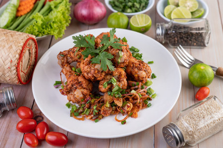 Spicy minced chicken on a white plate complete with cucumber, lettuce and side dishes on wooden table.