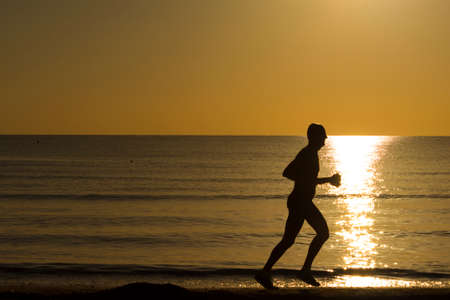 man running on the beach at dawnの写真素材
