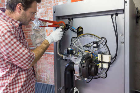 plumber repairing a condensing boiler in the boiler roomの写真素材