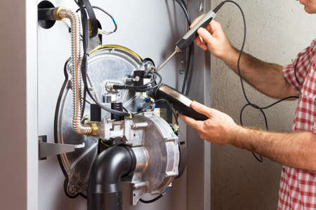 plumber repairing a condensing boiler in the boiler roomの写真素材