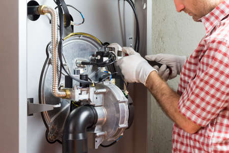plumber repairing a condensing boiler in the boiler roomの写真素材