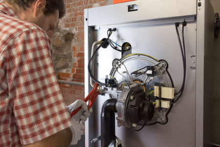 plumber repairing a condensing boiler in the boiler roomの写真素材