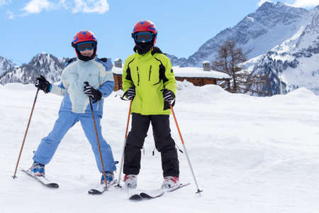 children on a ski slope with mountain background and snowの写真素材