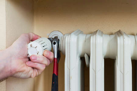 Plumber at work installing a thermostatic valve on a radiatorの写真素材