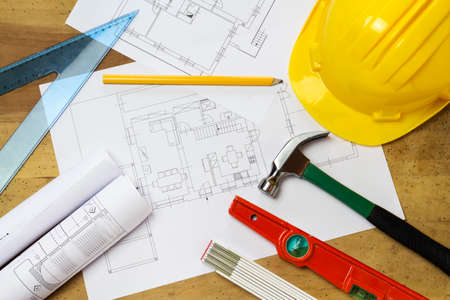 Protective helmet, mason tools and project drawings on wood backgroundの写真素材