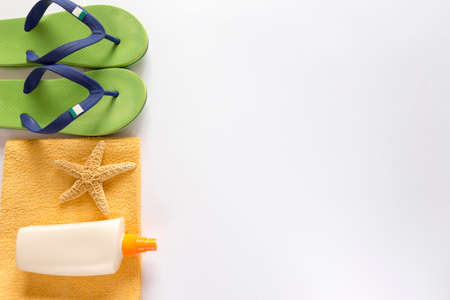 Sea slippers, sunscreen and towel on white backgroundの写真素材