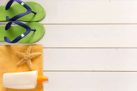 Sea slippers, sunscreen and towel on wooden backgroundの写真素材
