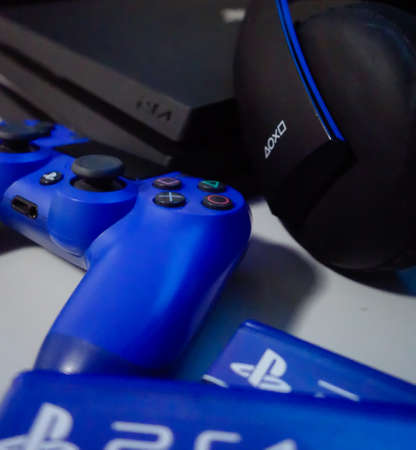 Sony black Playstation 4 Pro game console and blue wireless controller. PS4 symbol
