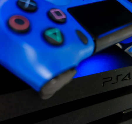 Sony black Playstation 4 Pro game console and blue wireless controller. PS4 symbol