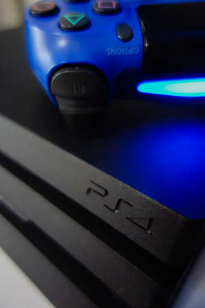 Sony black Playstation 4 Pro game console and blue wireless controller. PS4 symbol