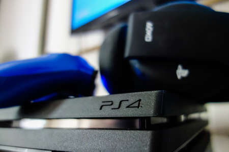 Sony black Playstation 4 Pro game console with blue wireless controller and gaming headset. PS4 symbolのeditorial素材