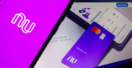 Nubank brazilian fintech logo visible on smartphone screen, and website homepage on backgroundのeditorial素材