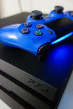 Sony black Playstation 4 Pro game console and blue wireless controller. PS4 symbol
