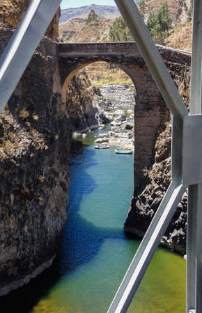 Arequipa, Peru: old arch bridge, cliffs and green waters of Colca riverの写真素材