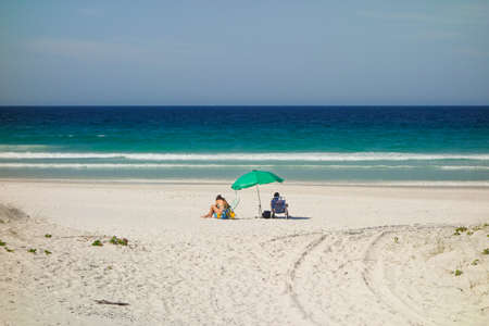 unidentified person under Beach Umbrella on the sand of Beautiful Clear Blue sea.の写真素材