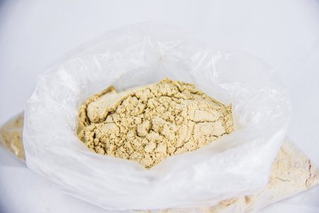 raw crushed dry ginger powder in transparent container, medical spicy aroma, isolated on white background, studio shot photography, selective focus, shallow depth of fieldの写真素材