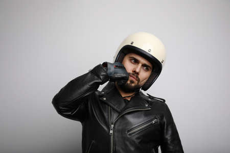 Young biker in a leather jacket pretending to ride a motorcycle isolated on a white background. Horizontal.の写真素材