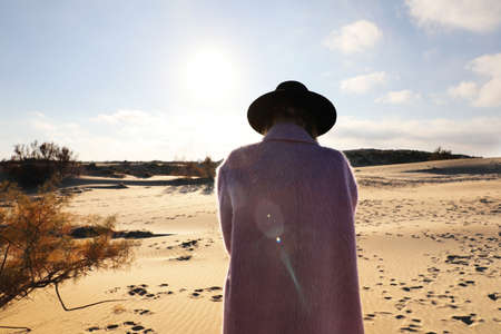 Young woman wearing pink suit and hat enjoying sunny weather.