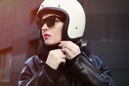 Close-up portrait of biker girl wearing white helmet. Outdoor.