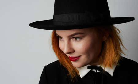 Portrait of hipster young woman wearing black dress and hat posing on the white wall. Isolated.の写真素材