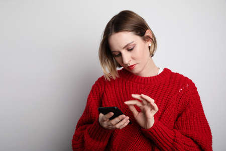 Stylish young woman wearing casual clothes and typing message from smartphone.の写真素材