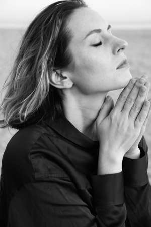 Young woman doing meditation on the beach. Black and white photo.の写真素材