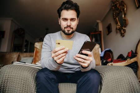 Bearded hipster man making order on-line using credit card. Grain texture.