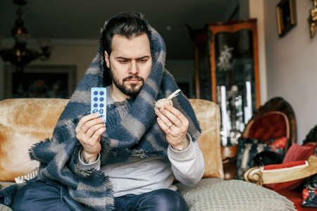 Bearded man having virus. Taking medicine at home.の写真素材