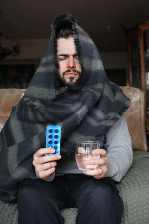 Bearded man having virus. Taking medicine at home and staying at home for quarantine.