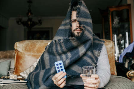 Bearded man having virus. Taking medicine at home.の写真素材
