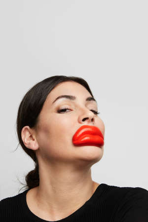 Dark Hair beautiful woman with red lips posing on the white background. Horizontal.の写真素材