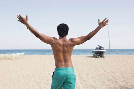 Headshot of black male, feeling happy to spend his free time very well staying against blue sea.の写真素材