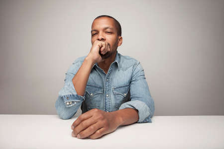 Young African American black man against white wall with serious face.
