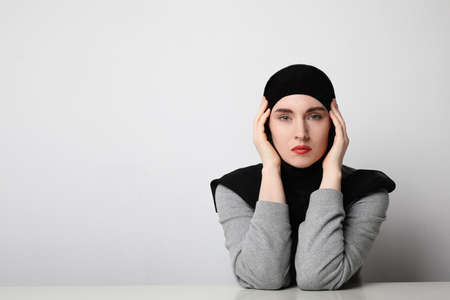 Muslim young woman wearing hijab posing on the white wall. Space for text.の写真素材