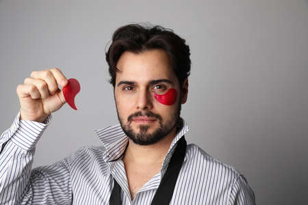 Horizontal photo of dark-haired bearded man with used eye patches. Skin care for man.