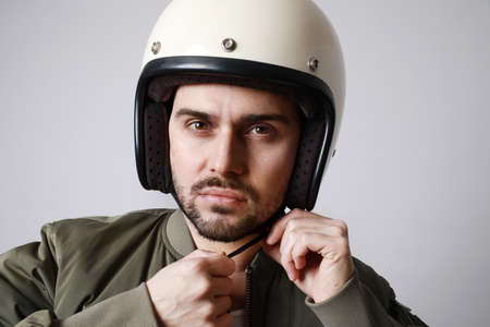 Handsome bearded man over white background with serious face trying adjust the helmet.