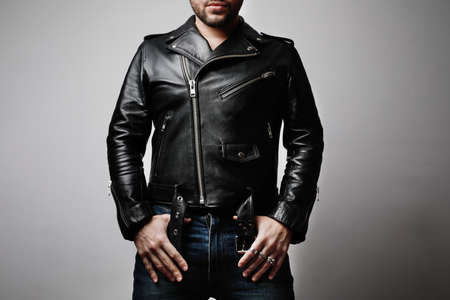 Portrait of man wearing leather jacket stands front in the studio.の写真素材