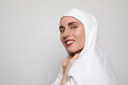 Side portrait of a beautiful young Muslim woman wearing a hijab on her head looking at the camera and smiling.の写真素材