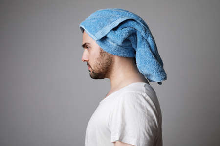 Bearded man in towel wearing white T-shirt, isolated on grey, hair care concept.の写真素材