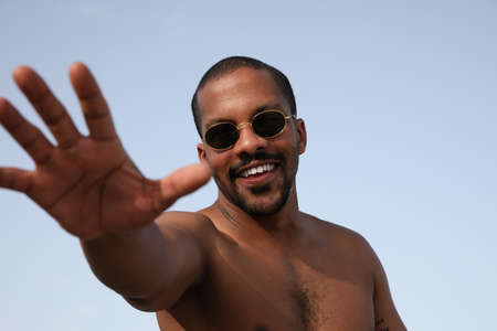 Outdoor portrait of bearded black handsome guy wearing sunglasses spending time on the beach.の写真素材
