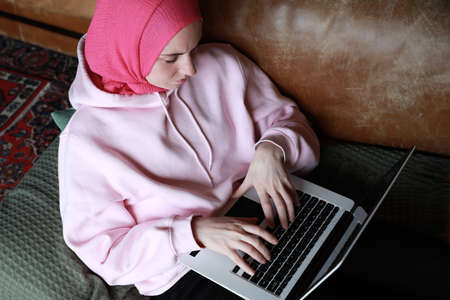 Portrait of a muslim woman working with computer wearing a head scarf. Isolated.の写真素材