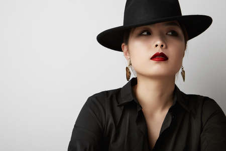 Beauty portrait of sensual asian young woman wearing black hat posing on white background. White background.の写真素材