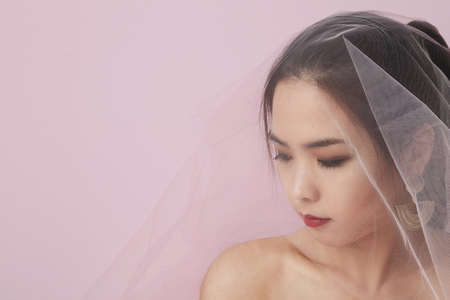 Close-up portrait of asian woman in bridal make up and hair style. Pink studio background. Space for your text.の写真素材