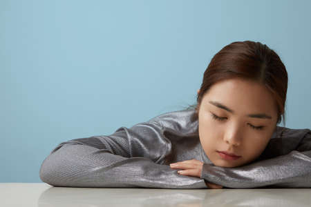 Head shot of cheerful happy asian young woman posing over blue background Isolated. Vertical...