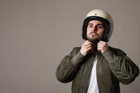 Brutal bearded biker man wearing retro helmet and dressed in a green bomber jacket. Free space for...